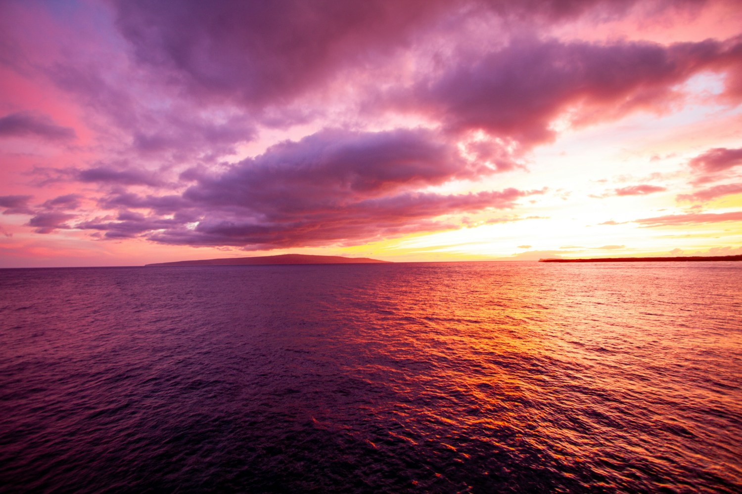 Vibrant sunset over the ocean with purple and orange skies.